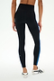 A person wearing SPLITS59 Ella High Waist Airweight 7/8 leggings in Black/Classic Blue and white sneakers stands against a plain light background.