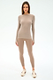 A woman faces forward in the SPLITS59 Louise Rib Long Sleeve - Latte and matching leggings—ideal beige-toned activewear for gym workouts—with white sneakers, set against a plain light background.