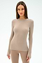 A woman with straight brown hair wears the SPLITS59 Louise Rib Long Sleeve in Latte with matching leggings, ideal for gym workouts, standing against a plain light background.