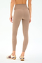 A person wears SPLITS59 Mia Rigor Legging w/ Stripe in Latte/White, high-waisted leggings with a white side stripe, paired with white sneakers with burgundy stripes, standing against a plain white background.