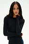 A woman with long braided hair wears the SPLITS59 Airweight Lite Long Sleeve Waist Length top in black, paired with matching black pants, as she stands against a white background and rests one hand on her neck. This fitted top is perfect for gym workouts, offering both comfort and style for every session.