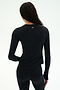 A person with long hair, seen from behind, is wearing the SPLITS59 Airweight Lite Long Sleeve Waist Length top in black paired with black leggings. This lightweight workout tee features subtle white branding near the collar, making it ideal for gym workouts.