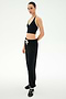 A person stands in a studio, facing forward with a neutral expression against a plain light background, wearing the SPLITS59 Andie Oversized Fleece Sweatpant in Black, styled effortlessly for cool weather workouts.