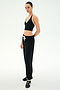 A person stands in a studio, facing forward with a neutral expression against a plain light background, wearing the SPLITS59 Andie Oversized Fleece Sweatpant in Black, styled effortlessly for cool weather workouts.