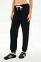 Wearing the SPLITS59 Andie Oversized Fleece Sweatpant in black, featuring a white drawstring, paired with classic black sneakers with white stripes—an ideal look for cool weather workouts, set against a plain white background.