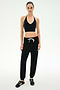Standing against a plain background, the person is wearing a black halter crop top, SPLITS59 Andie Oversized Fleece Sweatpant in Black—made in Los Angeles and featuring a white drawstring—and black sneakers with white stripes, creating the perfect outfit for cool weather workouts.