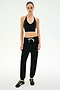 Standing against a plain background, the person is wearing a black halter crop top, SPLITS59 Andie Oversized Fleece Sweatpant in Black—made in Los Angeles and featuring a white drawstring—and black sneakers with white stripes, creating the perfect outfit for cool weather workouts.
