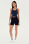 A woman stands wearing a navy blue SPLITS59 Ashby Rib Crop - Indigo, black shorts, and white socks against a plain white background.