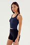 A person with long hair is wearing a navy SPLITS59 Ashby Rib Crop - Indigo and black shorts, standing against a plain white background.