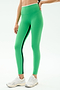 A person wearing SPLITS59 Easton Rigor High Waist 7/8 leggings in Grass/White, featuring a bright green compressive fabric with a black side stripe, paired with white athletic shoes and standing against a plain light background.