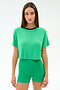 A woman wears the SPLITS59 Djuna Crop Ringer in Spearmint/Indigo, paired with green high-waisted shorts, both crafted from soft viscose fabric, standing against a plain light background.