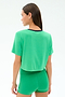 A woman faces away against a plain light background, wearing the SPLITS59 Djuna Crop Ringer in Spearmint/Indigo— a green cropped t-shirt made from soft viscose fabric.