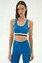 A woman wears the SPLITS59 Maci Airweight Bra in Stone Blue/Graphite with matching high-waisted leggings, standing against a plain light background.