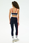 A woman with curly hair is seen from behind in a SPLITS59 Eva Rigor Double Strap Bra - Indigo/White, looking comfortable and confident for gym workouts against a plain white background.