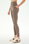 A person is standing against a plain white background wearing SPLITS59 Airweight High Waist 7/8 Pocket Legging in Lentil, paired with white sneakers featuring maroon stripes.