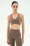 Woman wearing the SPLITS59 Airweight Bra With Ruching in Lentil and matching high-waisted leggings, standing against a plain light background.