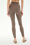 A person wearing SPLITS59 Airweight High Waist 7/8 Pocket Legging in Lentil and sneakers stands facing away against a plain, light background.