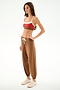 Woman in profile against a white background, wearing a red sports bra, SPLITS59 Andie Oversized Fleece Sweatpant - Toffee, and beige sneakers.
