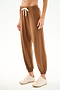 Person wearing SPLITS59 Andie Oversized Fleece Sweatpant - Toffee with a white drawstring and cream sneakers, standing against a white background.