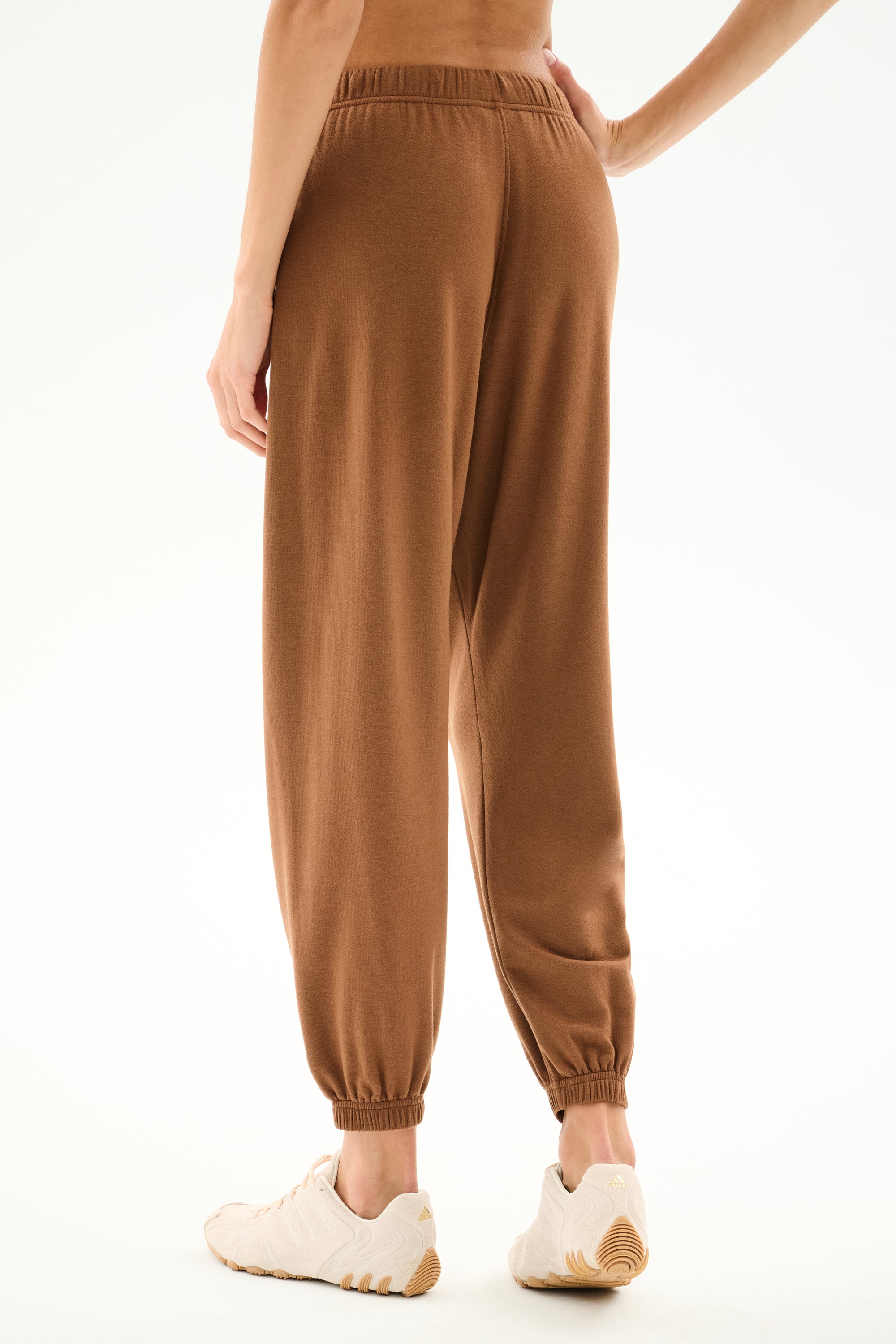Model wears SPLITS59 Andie Oversized Fleece Sweatpant - Toffee with white sneakers, shown from the back against a plain white background.