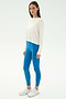 A woman wears the SPLITS59 Djuna Long Sleeve in white, styled with bright blue leggings and white athletic shoes—ideal for gym or outdoor workouts—posed against a plain white background.