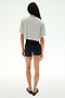 A person stands facing away against a white background, wearing SPLITS59's Djuna Oversized Crop Jersey Tee in Heather Grey, paired with black shorts and black flats.