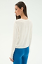 A woman stands sideways against a light background, wearing the SPLITS59 Djuna Long Sleeve in white and bright blue leggings.