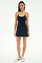 A woman faces forward wearing the SPLITS59 Ella Airweight Dress in Indigo/Bright Yellow, made from a nylon-spandex blend, paired with white sneakers against a plain white background.