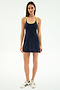 A woman faces forward wearing the SPLITS59 Ella Airweight Dress in Indigo/Bright Yellow, made from a nylon-spandex blend, paired with white sneakers against a plain white background.
