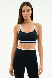 A woman stands against a plain background wearing the SPLITS59 Eva Rigor Double Strap Bra in Black/Skylight with matching high-waisted leggings.