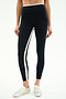 Wearing SPLITS59 Sam High Waist Rigor 7/8 leggings in Black/Skylight with white side stripes and silver sneakers, standing against a plain background.
