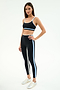 A woman models the SPLITS59 Sam High Waist Rigor 7/8 - Black/Skylight leggings with a matching black sports bra and white sneakers, set against a plain white background.