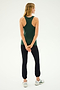 A person with long blonde hair is seen from the back, wearing a green sleeveless top, the Icon High Waist Supplex Legging in black from SPLITS59, and white sneakers, standing with hands clasped behind.