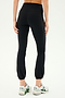 Person wearing the SPLITS59 Icon High Waist Supplex Legging in black paired with white athletic shoes, shown from the back. The plain white background emphasizes the slim fit of the legging.