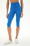 Model wearing SPLITS59 Airweight High Waist 16" Capri Legging in Classic Blue, paired with white athletic shoes, standing against a plain white background.