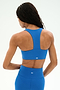 A person with long braided hair wears the SPLITS59 Sara Airweight Bra in Classic Blue and matching leggings, both made from a soft nylon-spandex blend, shown from the back against a plain light background.