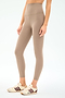 A person in SPLITS59 Airweight Super High Waist 7/8 leggings in Latte—made from ultra luxe Airweight fabric—and cream sneakers with burgundy stripes, stands against a plain white background. Ideal for hot yoga or casual wear.