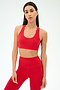 A woman with long dark hair wears the SPLITS59 Sara Airweight Bra in Pirate Red and matching high-waisted leggings against a plain light background—ideal for hot yoga or Pilates.
