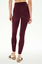 A person is shown from the back, standing against a plain white background, wearing the SPLITS59 Airweight High Waist 7/8 Pocket Legging in Dark Cherry and beige sneakers with maroon stripes.