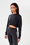 A woman wearing a SPLITS59 Noah Fleece Crop Sweatshirt in Graphite and athletic leggings.