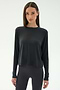 A woman stands facing forward in the SPLITS59 Djuna Long Sleeve - Graphite top and black leggings, set against a plain light background.