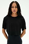 A person with long braided hair wears the SPLITS59 Djuna Oversized Crop Jersey Tee in black and black pants, standing against a plain white background.