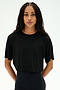 A person with long braided hair wears the SPLITS59 Djuna Oversized Crop Jersey Tee in black and black pants, standing against a plain white background.