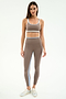 A woman models the SPLITS59 Eva Rigor Double Strap Bra in Lentil/White with coordinating leggings and silver sneakers against a white background—ideal for your next workout or yoga session.