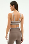 Woman wearing the SPLITS59 Eva Rigor Double Strap Bra in Lentil/White with matching high-waisted leggings, standing with her back to the camera—ideal as a yoga or workout bra for an active lifestyle.