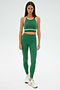A person wearing the SPLITS59 Layla Airweight Bra in Arugula/Indigo, with matching leggings and white sneakers, stands against a plain background.