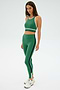 A person wearing the SPLITS59 Layla Airweight Bra in Arugula/Indigo and leggings stands against a plain background, complete with sneakers.