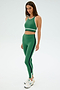 A person wearing the SPLITS59 Layla Airweight Bra in Arugula/Indigo and leggings stands against a plain background, complete with sneakers.