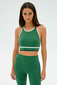 A person wearing a SPLITS59 Layla Airweight Bra in Arugula/Indigo and matching leggings stands against a plain background.