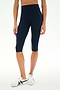 A person wearing SPLITS59 Airweight High Waist 16" Capri Legging in Indigo and white sneakers, shown from shoulders to feet, standing against a plain white background.